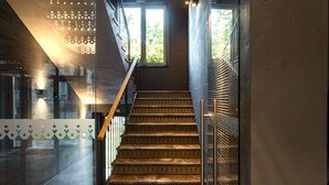 Una escala amb carpeta estampada i baranes metàl·liques, que condueix a una habitació amb un gran finestral.