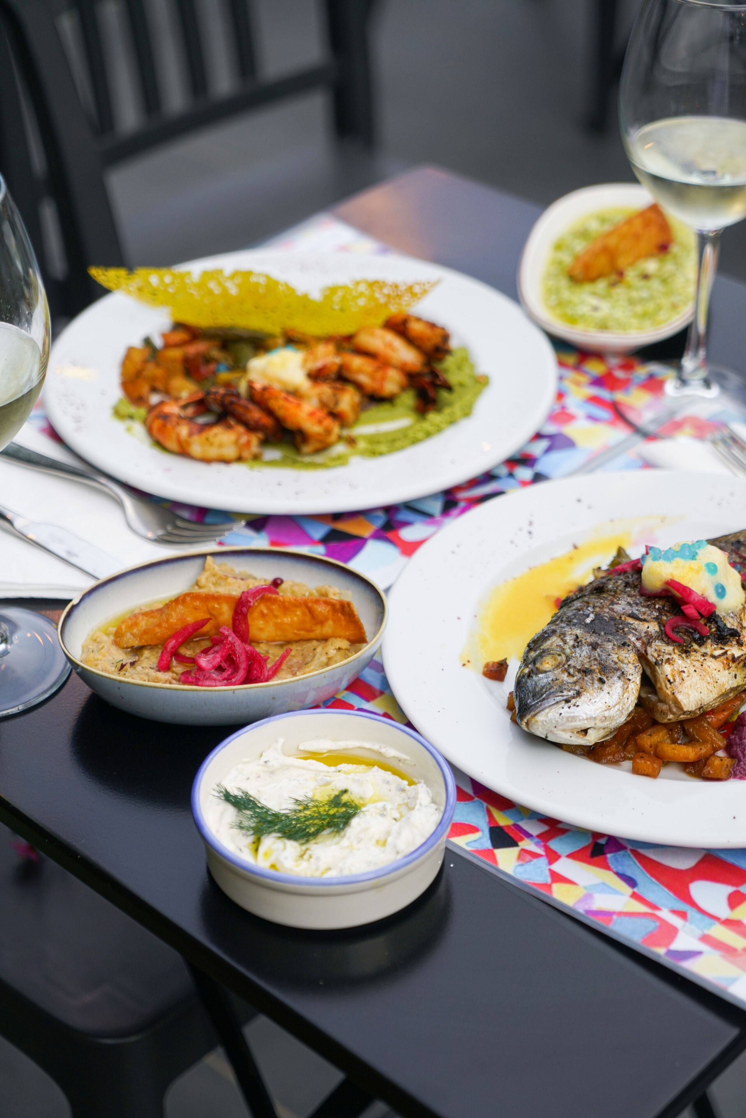 Ein Tisch mit verschiedenen Speisen, darunter Fisch, Garnelen und einer Dip-Schale.