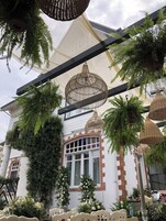 Un edificio con fachada blanca, ventanas grandes y un balcón con plantas.