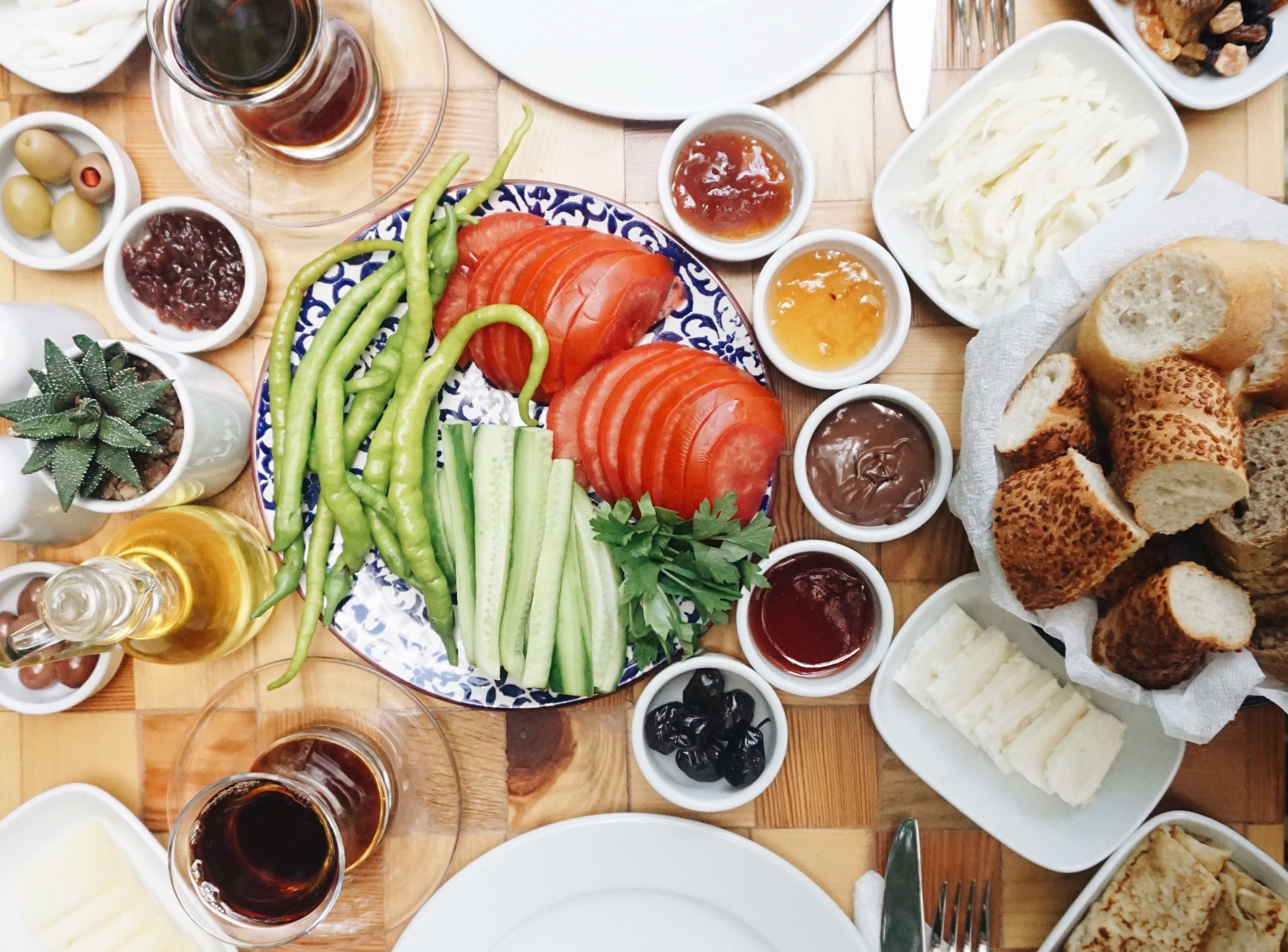 Una mesa con diferentes platos, incluyendo tomates en rodajas, pepinos, aceitunas y pan.