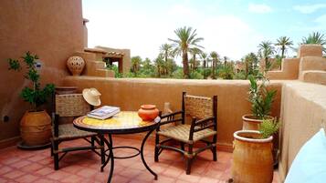A terrace with two wicker chairs, a small round table, and a potted plant.