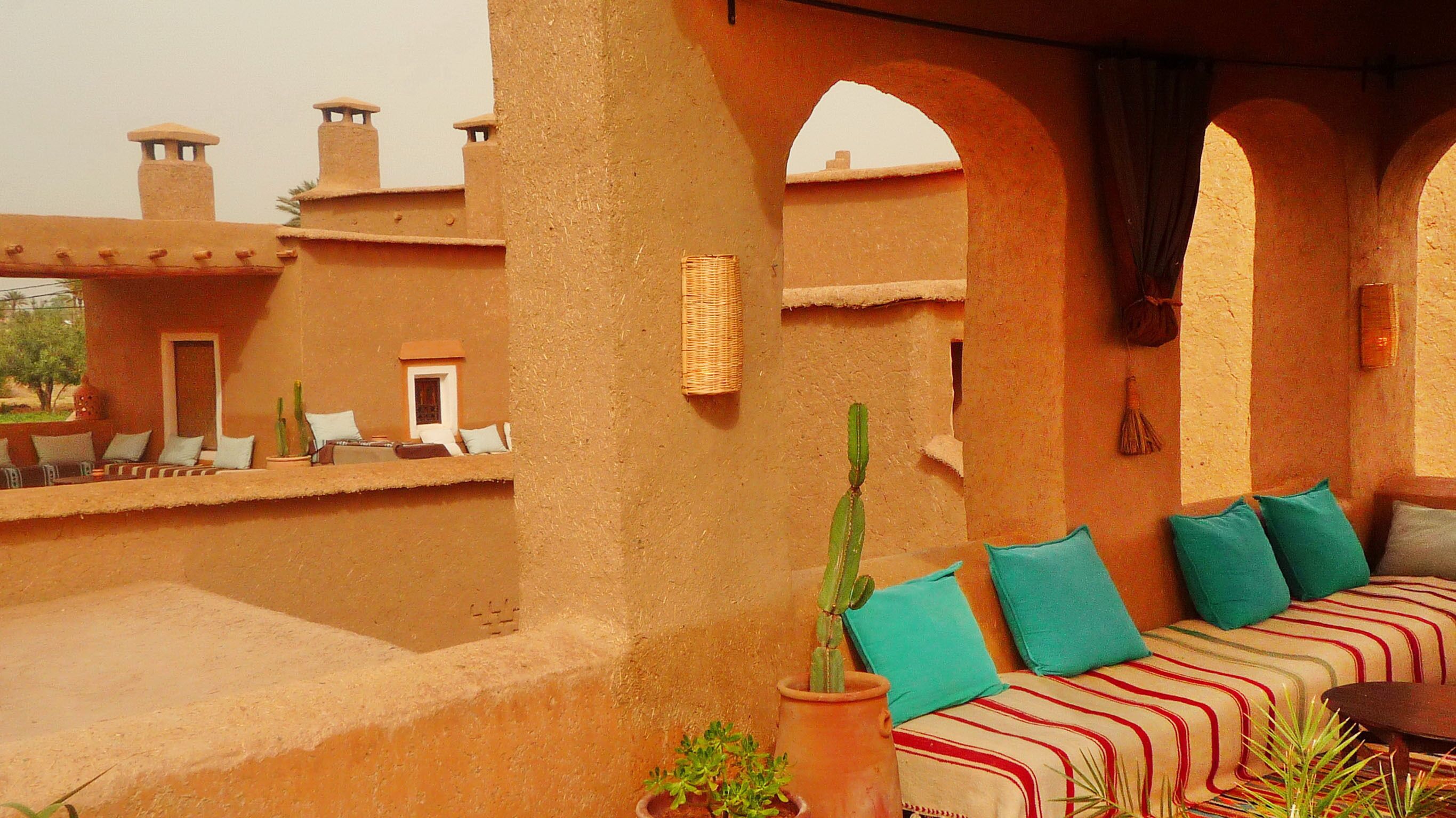 A terrace with a sofa, cushions, and potted plants.