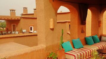 A terrace with a sofa, cushions, and potted plants.