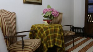 A room with striped chairs, a table with a checkered tablecloth, a vase with flowers, and a bookshelf. - Tourist House Santa Croce (Florence)