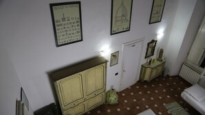 A room with a tiled floor, a bed, a wardrobe, a door, and framed pictures on the wall. - Tourist House Santa Croce (Florence)