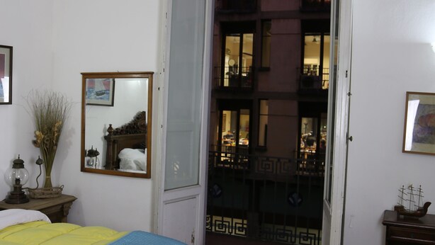 A bedroom with a bed, a bedside table, a mirror, and a view of the outside balcony. - Tourist House Santa Croce (Florence)