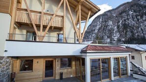 A modern building with a wooden facade, a balcony, and a mountain backdrop. - Chalet Marcora (Campitello di Fassa)