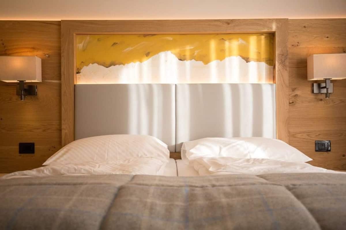 A hotel room with a wooden headboard, two bedside lamps, and a bed with white linens.