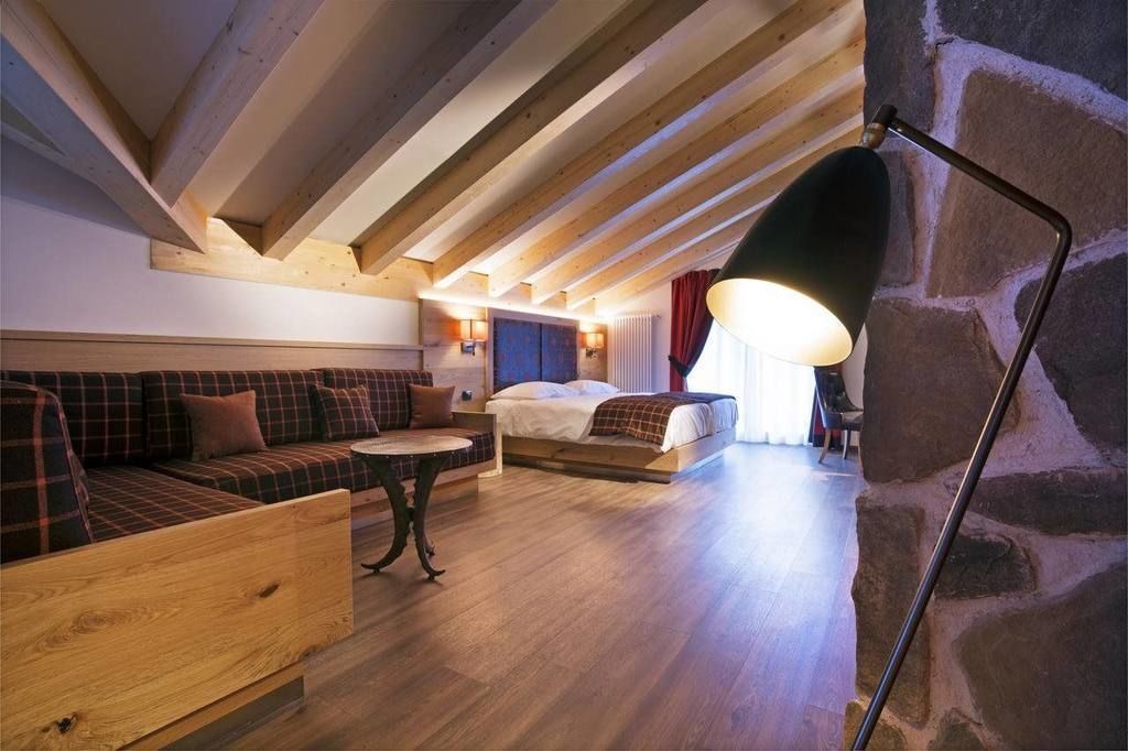 Una stanza accogliente con soffitto in legno, un divano, un letto, un tavolo e una lampada.