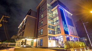 A modern hotel with multiple floors, large windows, and a prominent illuminated sign. - PSG Hotel (Udon Thani)