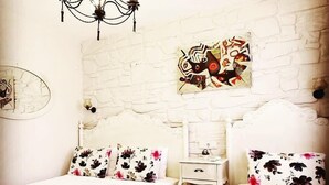 A bedroom with two beds, a nightstand, a chandelier, and a wall art piece. - Stafilia Bozcaada - Adults Only (Bozcaada)