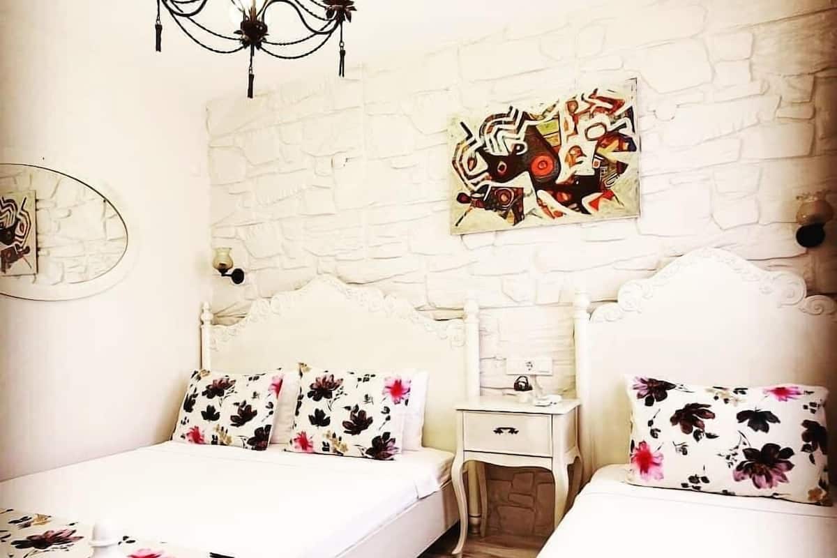 Ein Schlafzimmer mit zwei Betten, einem Nachttisch, einer Pendelleuchte und einem Wandbild.