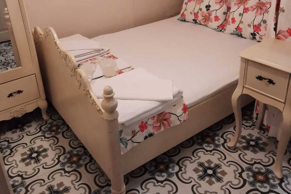 Ein Schlafzimmer mit Bett, Nachttisch, Kommode und Wandlampe.