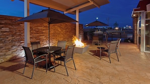 Un patio al aire libre con una chimenea, paredes de piedra y una zona de estar techada.