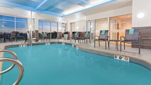 Una piscina interior con agua cristalina, una marca de profundidad de 15 metros y sillones de descanso con toallas.