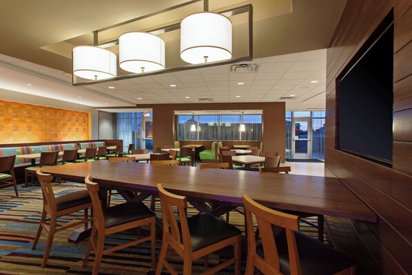 A conference room with a long table, multiple chairs, and a large screen.