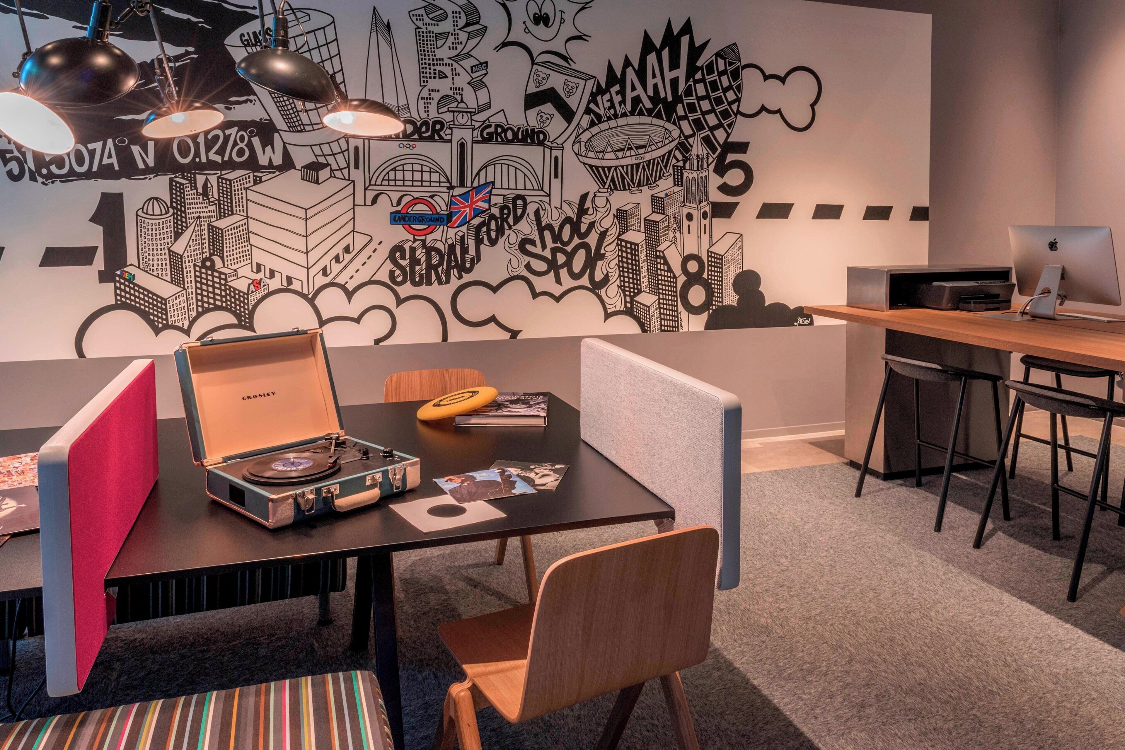 A modern office space with a cityscape mural, a vintage record player, and a desk with a computer.