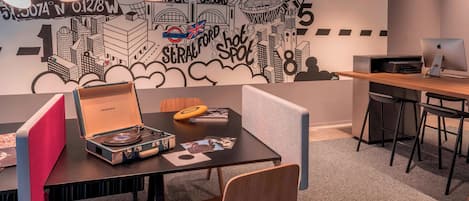 A modern office space with a cityscape mural, a vintage record player, and a desk with a computer.