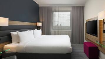 A modern hotel room with a large bed, a flat-screen TV, a desk with a chair, and a city view through the window.