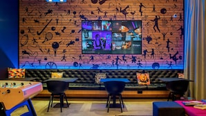 Ein moderner Lounge-Bereich mit einem großen Bildschirm, der eine Social-Media-Plattform zeigt, einem Kicker und bequemen Sitzgelegenheiten.