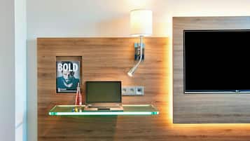 A modern room with a wooden wall, a glass shelf holding a laptop, a lamp, and a poster.