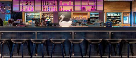 A bar area with a neon sign, a large white swan decoration, and multiple shelves stocked with bottles.