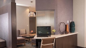A modern living room with a sofa, a coffee table, a TV, and a bar area with a laptop and decorative items.
