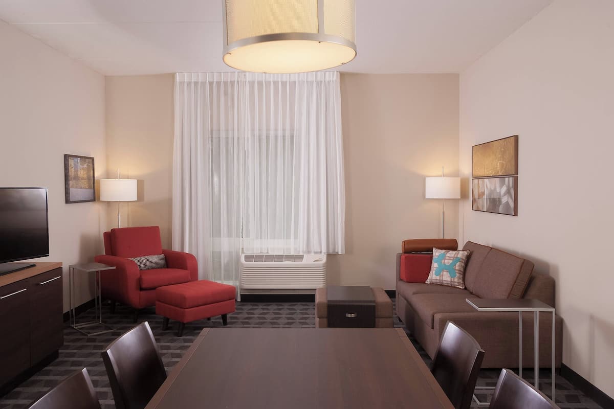 Une chambre d’hôtel équipée d’une table à manger, de deux canapés, d’un téléviseur et d’une lampe.
