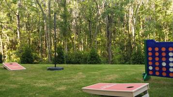 A grassy outdoor area with two red game boards and a blue and orange structure.