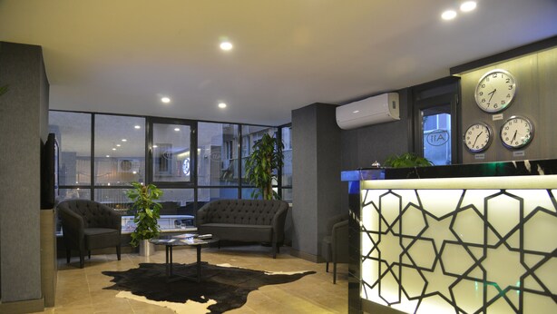 Um lobby moderno com uma mesa de recepção, sofás de couro, uma mesa de centro e uma janela ampla com vista para a cidade.