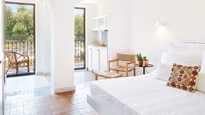 Un dormitorio amplio con una cama grande, una zona de comedor con sillas y vistas a una piscina y jardín.