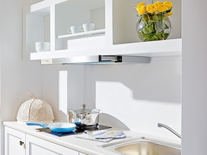 A modern kitchen with white cabinetry, a stainless steel sink, and a pot on the stove. - Grecotel Villa Oliva (Rethymno)