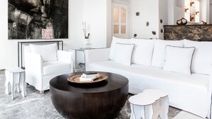 Una sala de estar moderna con un sofá blanco, una mesa de centro redonda y un cuadro abstracto grande.