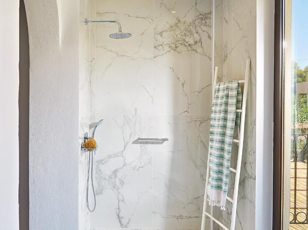 A bathroom with a shower, a towel rack, and a view of the outside.