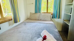A hotel room with a bed, curtains, a window, and a shelf. - Playa Mango (Bocas del Toro)