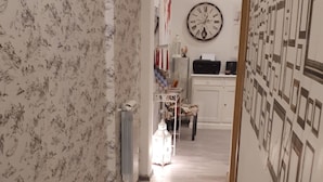 A hallway with patterned wallpaper, a clock, and a wall with framed pictures. - Gate of Paradise Florence B&B (Florence)