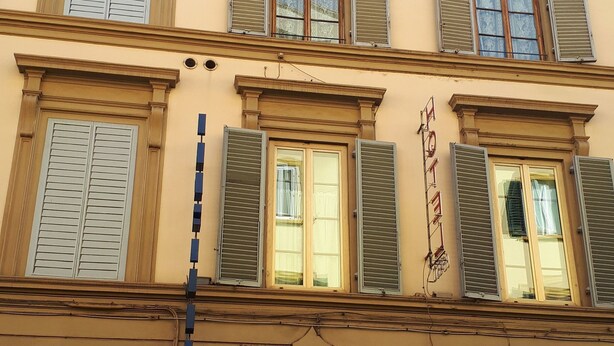 A building with multiple windows, some with shutters, and a storefront with a sign reading "LAKMALI GROC". - Gate of Paradise Florence B&B (Florence)