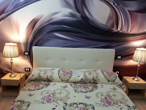 A bedroom with a large bed, two bedside lamps, and a decorative wall mural.