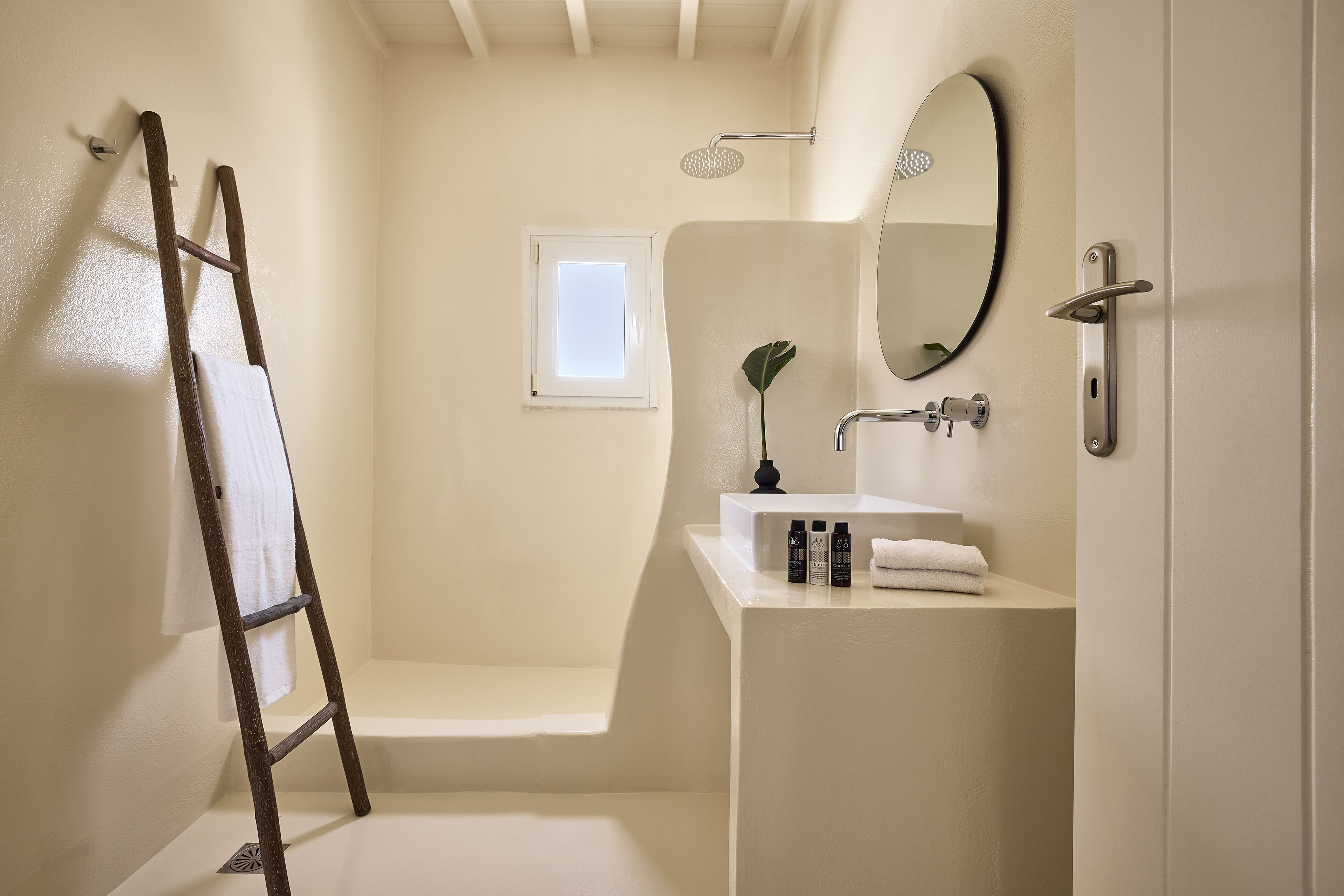 A bathroom with a bathtub, a window, a sink with toiletries, and a towel rack.
