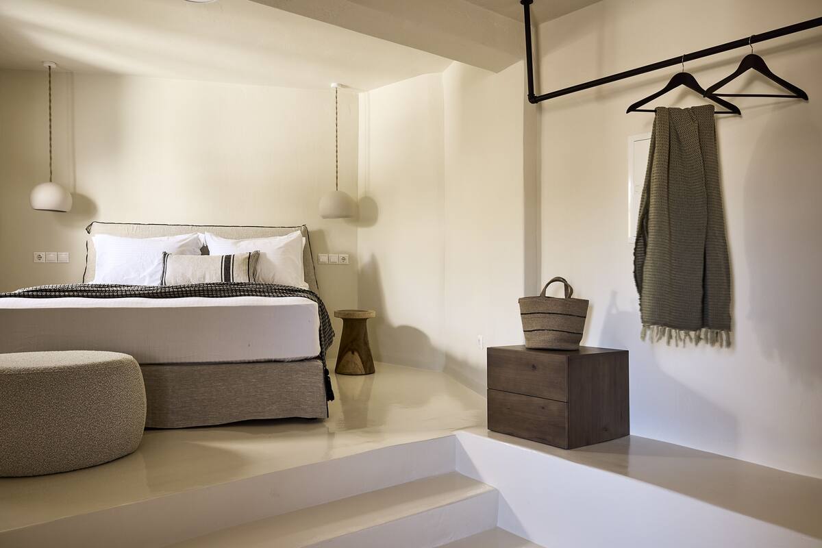 A minimalist bedroom with a bed, bedside table, and a hanging light fixture.