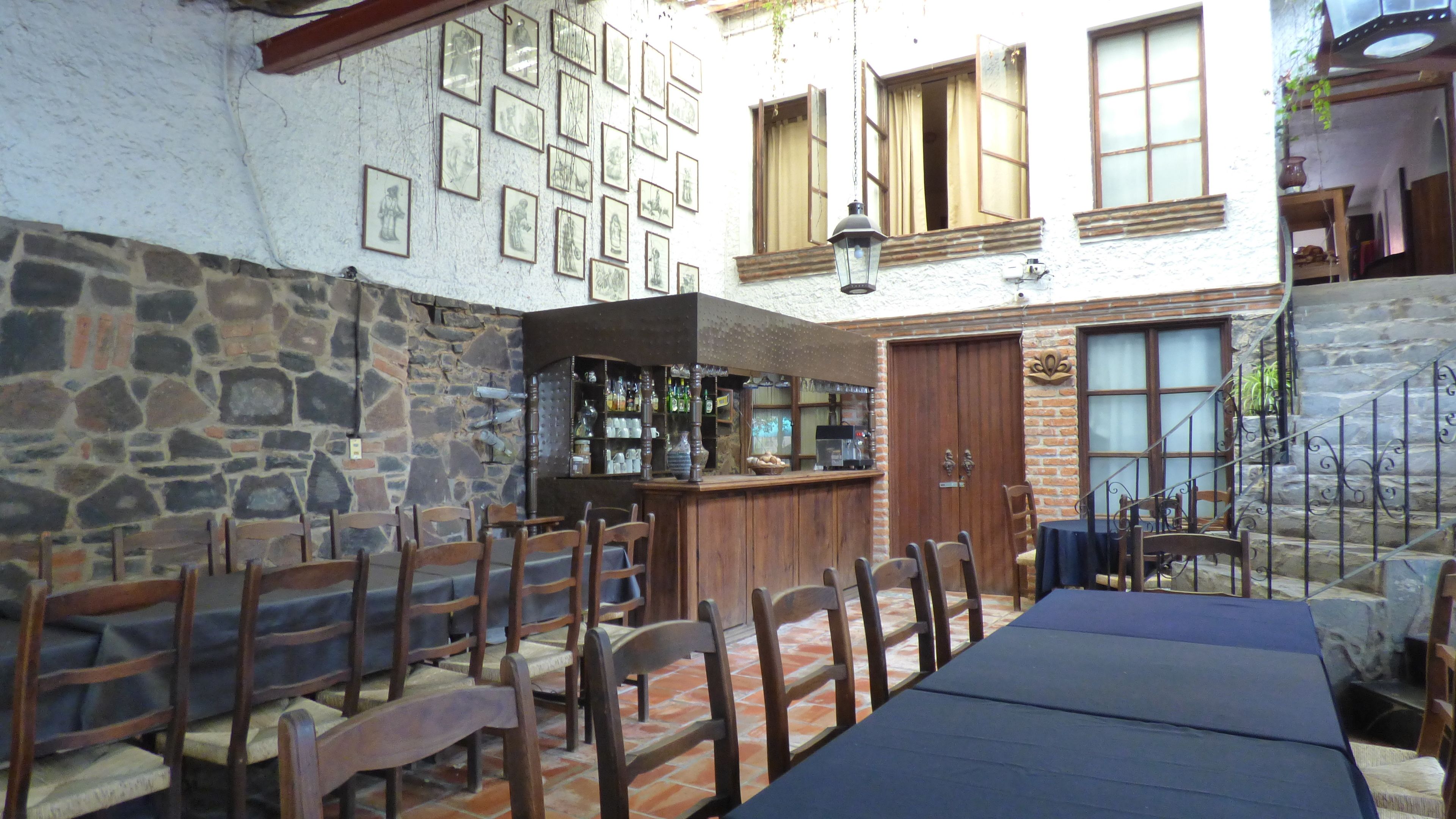 Un restaurant aux murs de pierre, aux chaises en bois, doté d’un bar et dont le sol est recouvert de carreaux.
