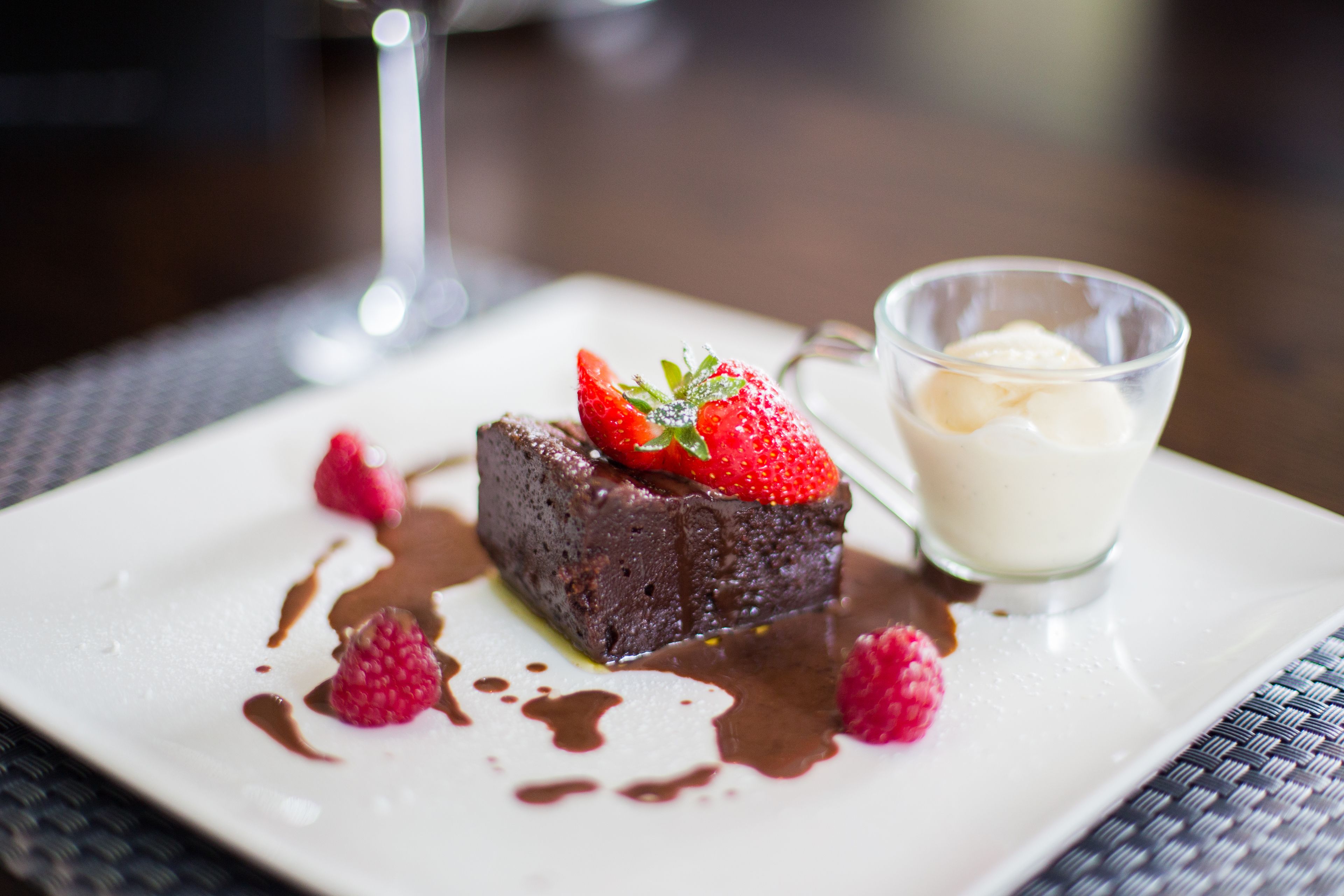 A dessert plate with a chocolate cake, strawberries, raspberries, and a glass of ice cream.
