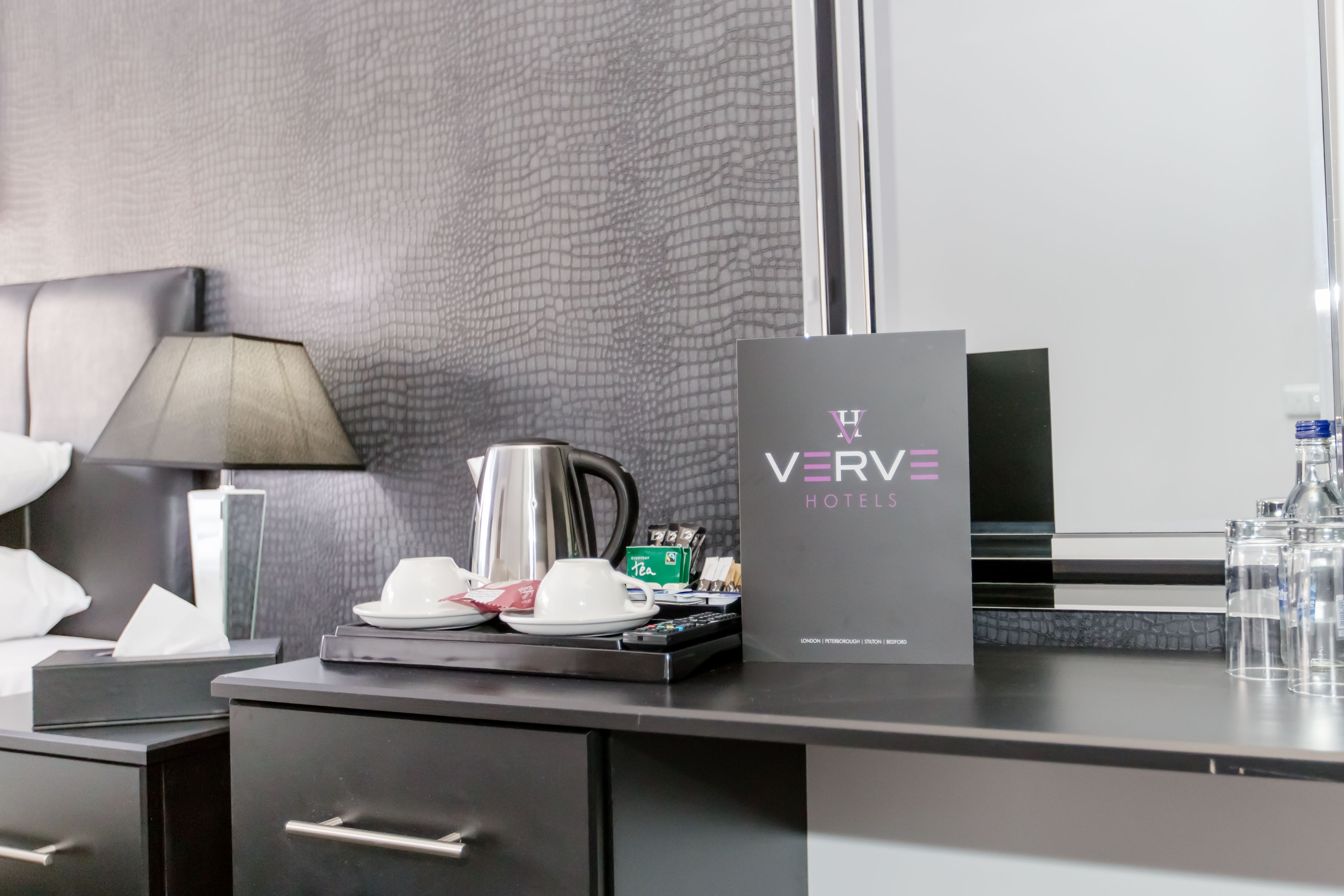 Mostrador de recepción de hotel con cafetera, servicio de té y un letrero de Verve Hotels.