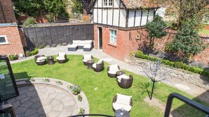 Un cortile con posti a sedere all'aperto, una scala e vista su un edificio in stile Tudor.