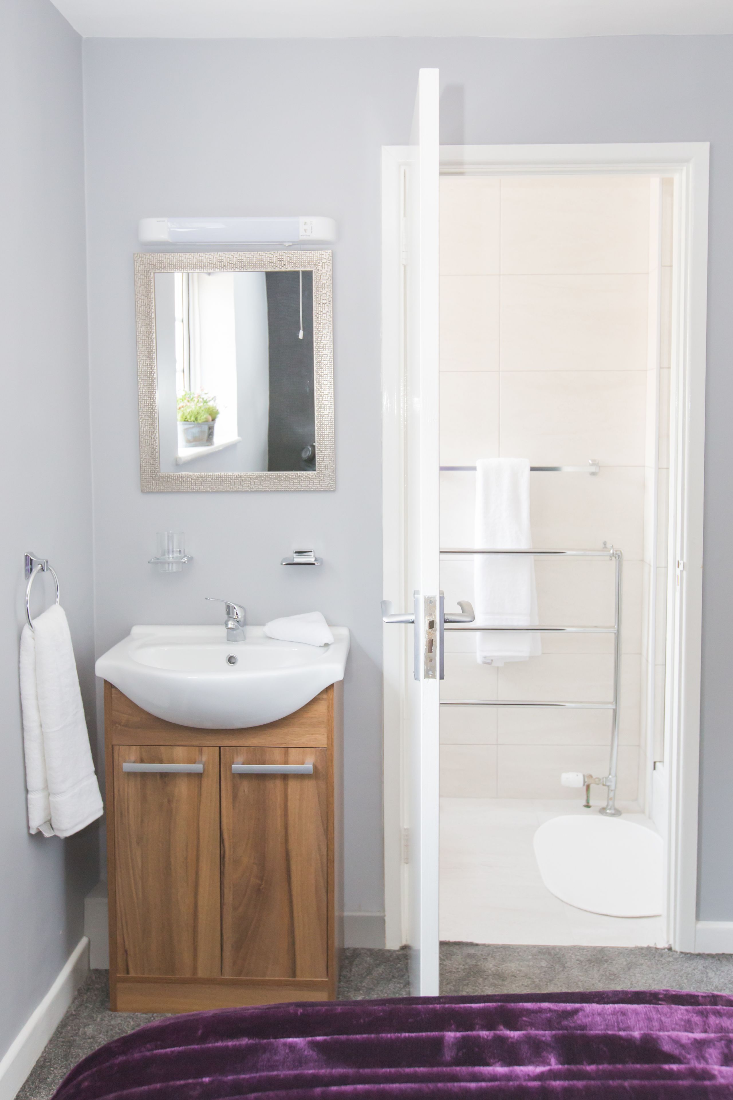 Une salle de bain avec un meuble-lavabo en bois, un lavabo blanc, un miroir et une cabine de douche en verre.
