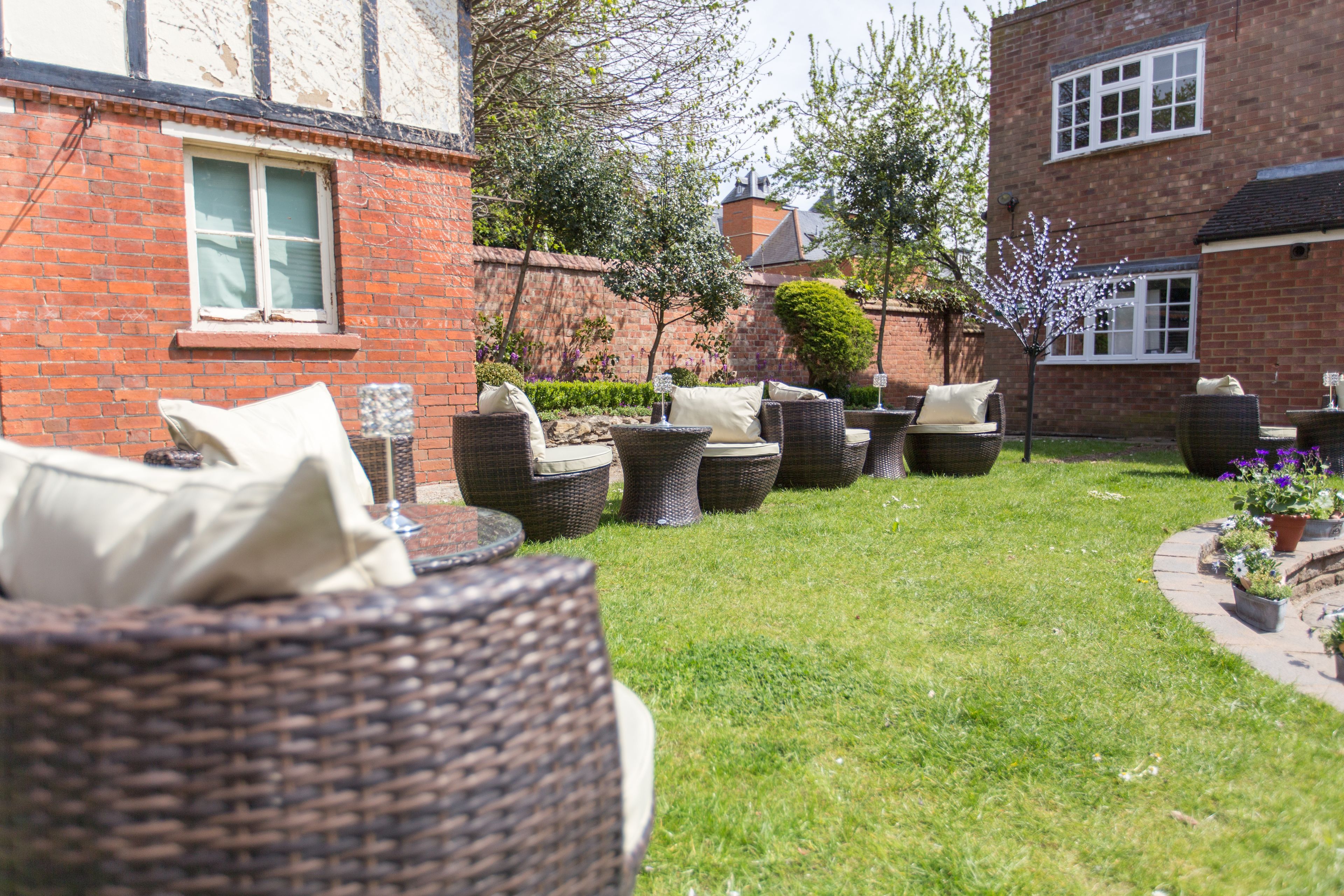 A garden with wicker furniture and a brick building.