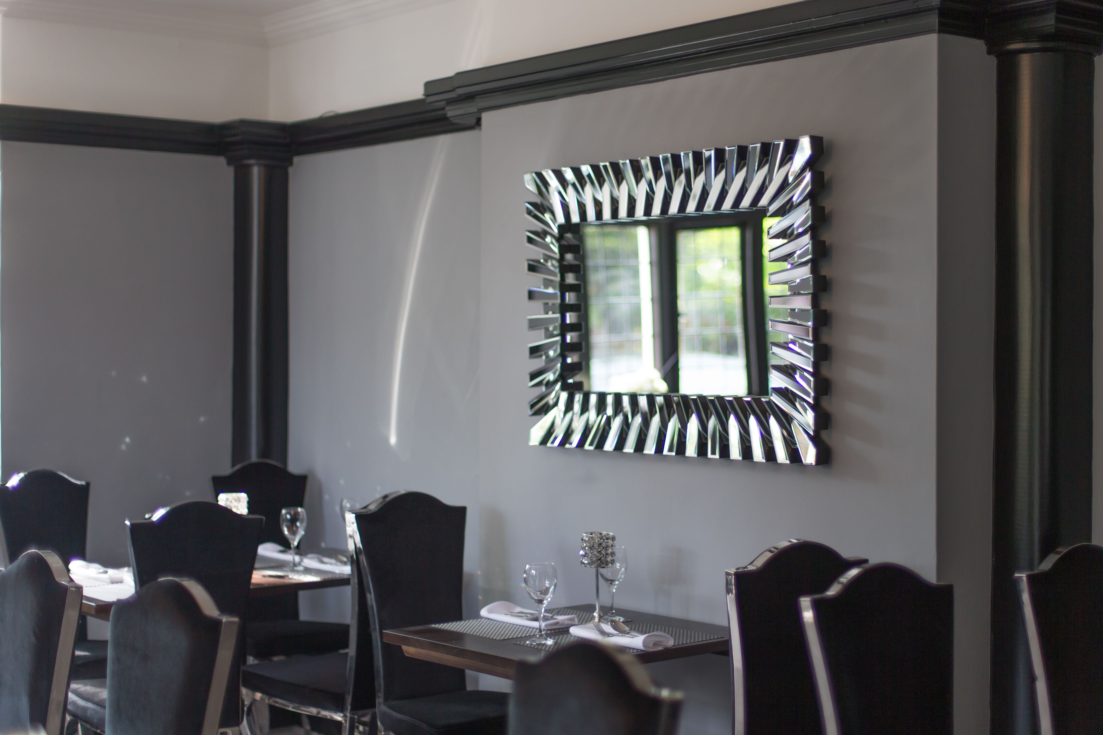 Ein Essbereich mit einem Tisch für zwei Personen, Stühlen und einem dekorativen Spiegel an der Wand.