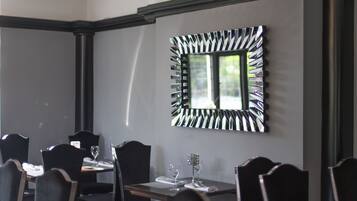 Ein Essbereich mit einem Tisch für zwei Personen, Stühlen und einem dekorativen Spiegel an der Wand.