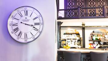 Un reloj de pared con números romanos y la inscripción '49 Bond Street London' sobre una pared blanca.