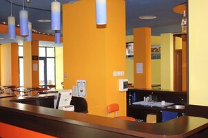 Zona de recepción de un hotel con mostrador, asientos y una ventana.